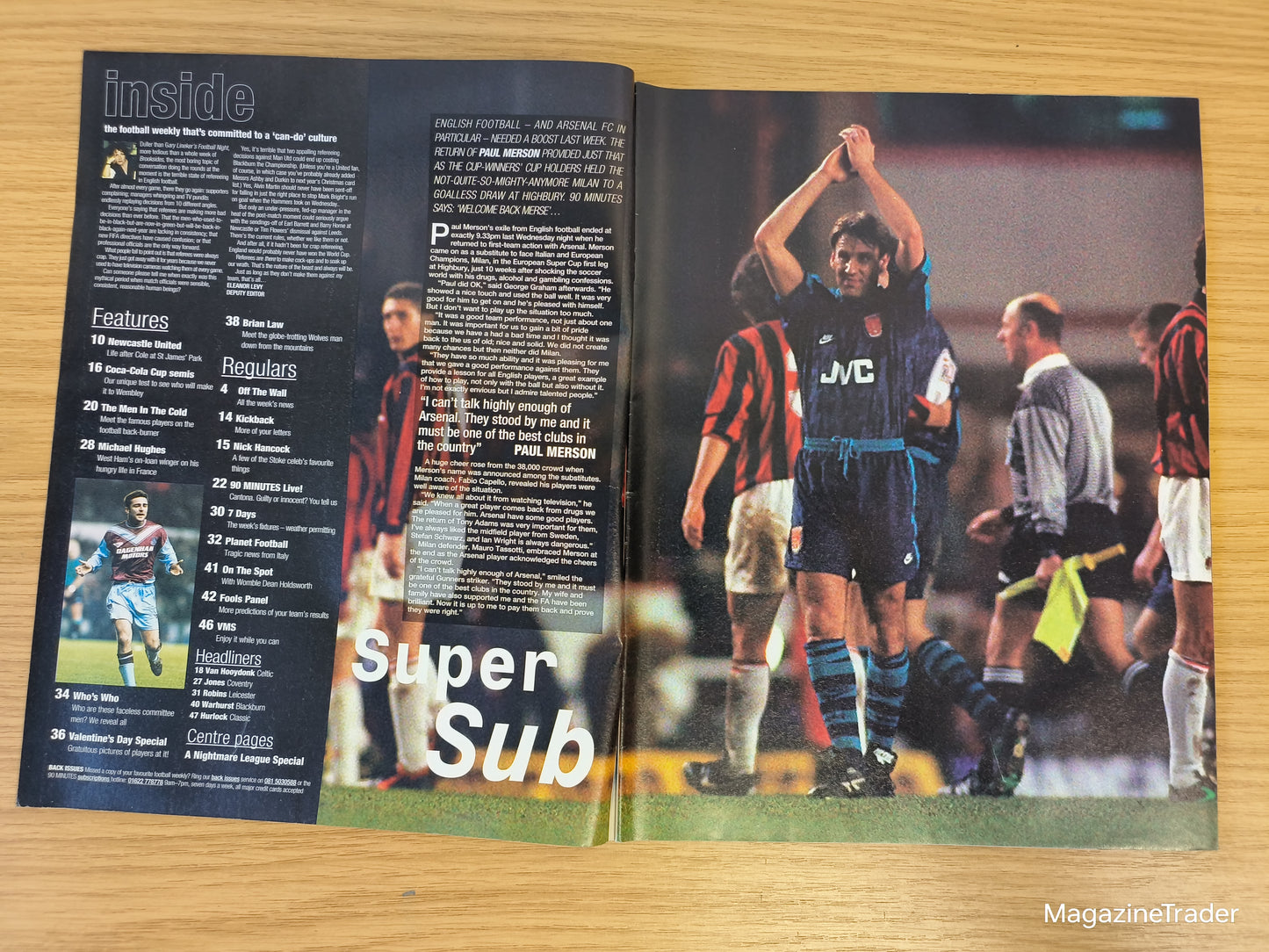 Open magazine showing a soccer article with players on a wooden surface