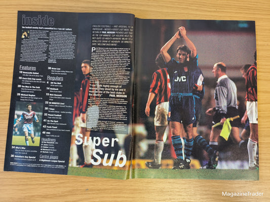 Open magazine showing a soccer article with players on a wooden surface